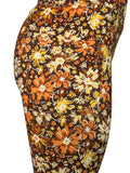 Close-up of a floral-patterned garment, likely leggings or a skirt, featuring a retro 1970s style print with orange, yellow, and cream flowers on a dark brown background.